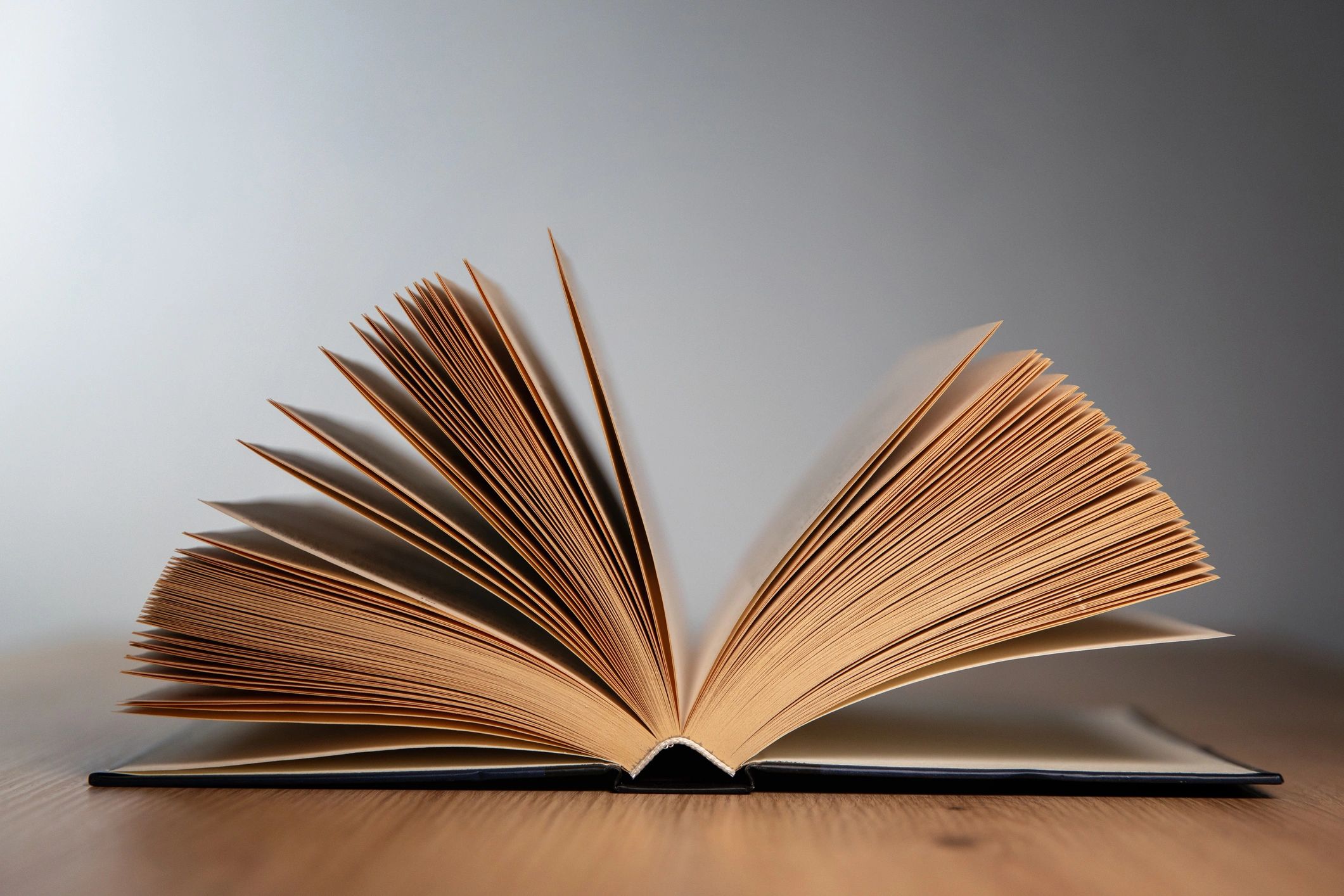 Open book on a wooden table in soft dramatic light